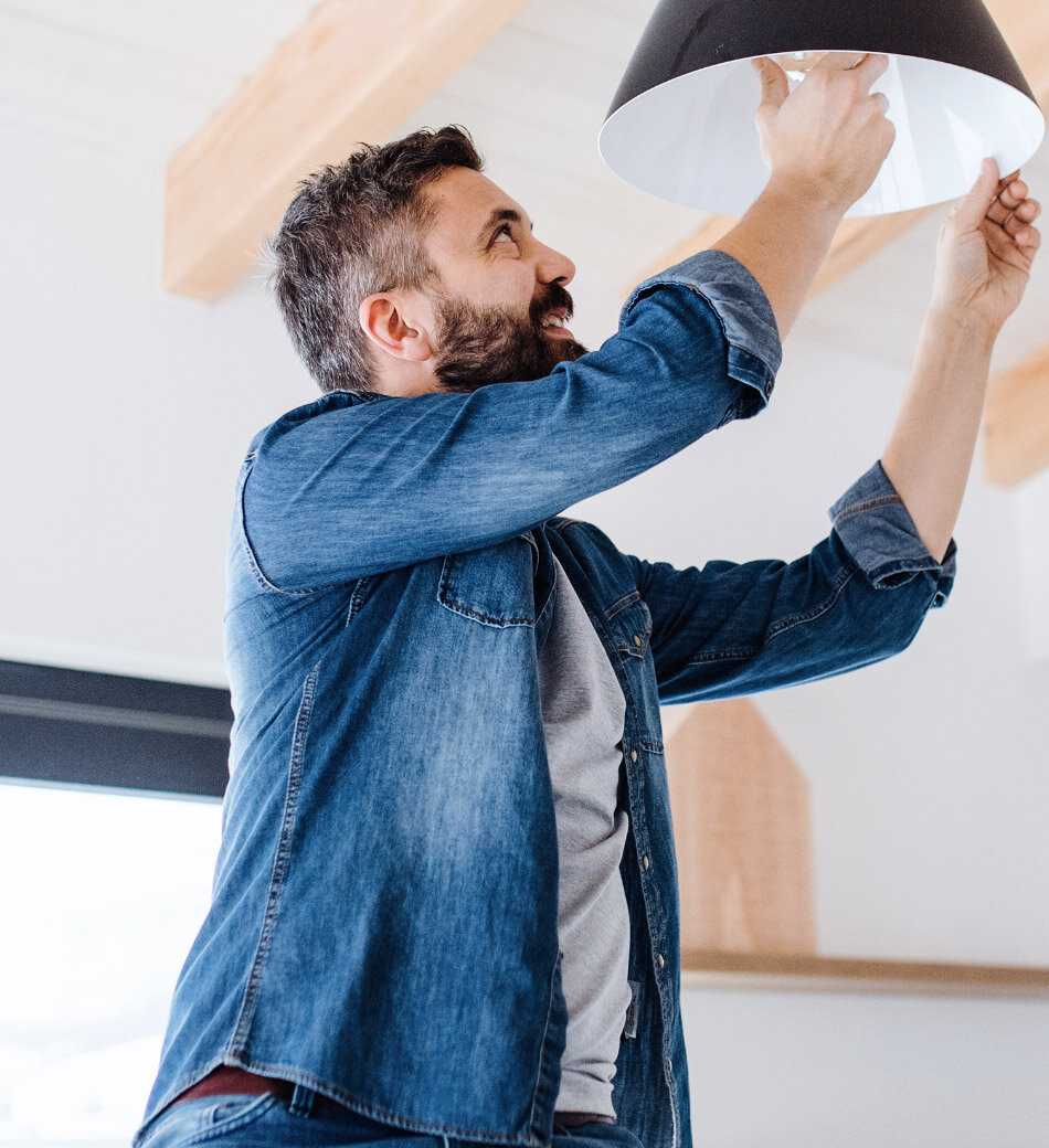 A man standing on a ladder and change the light bulb